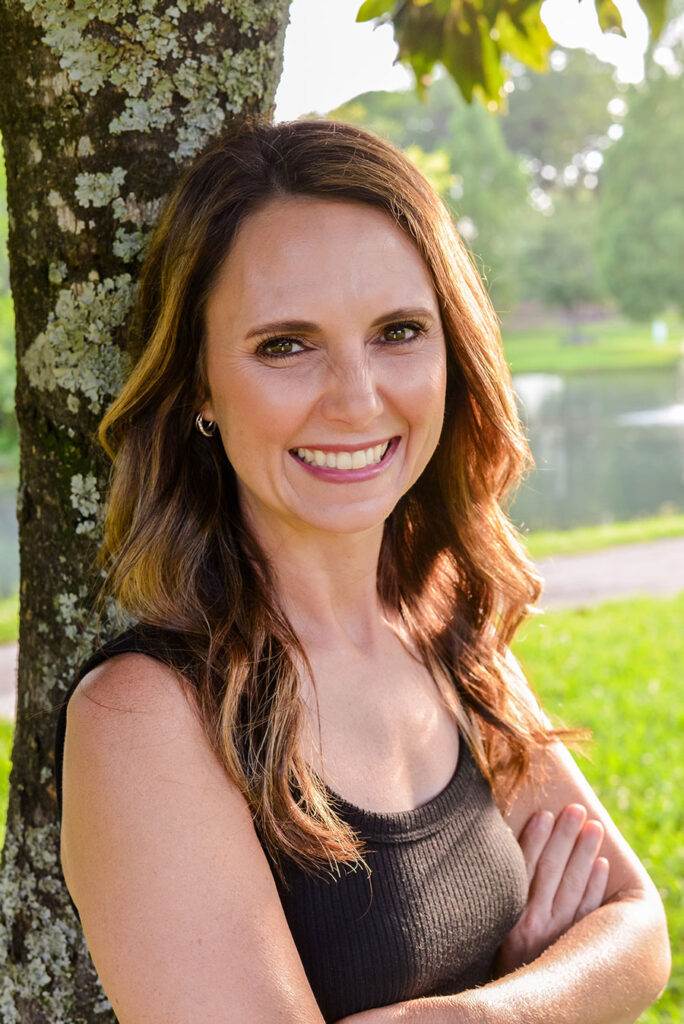 adult-woman-smiling-with-back-against-tree